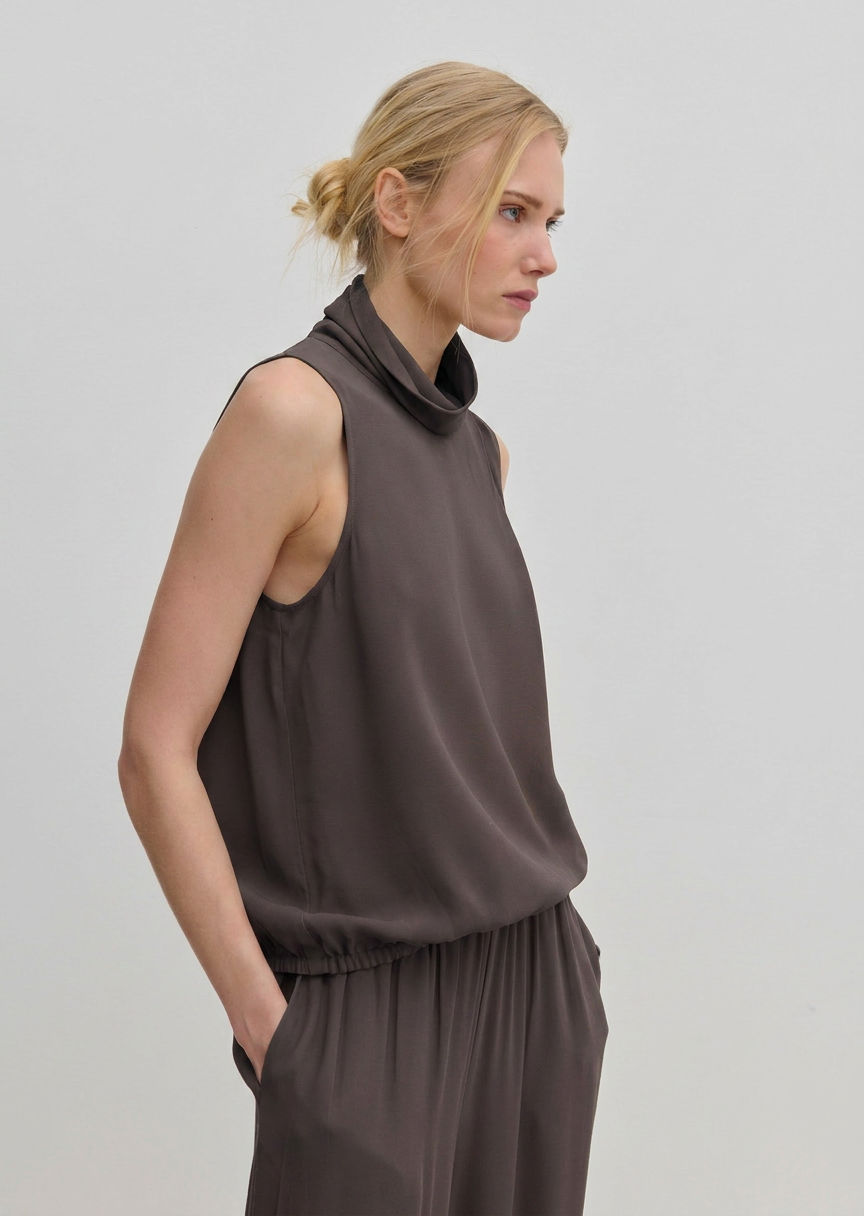 The Herskind ApS Loa Top is a sleeveless, brown FSC viscose top featuring a high, draped cowl neckline and a gathered hem.