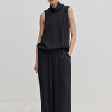 A person wearing a sleeveless black turtleneck top and matching black Nya Pants with an elasticated waist and loose-fitting, balloon leg silhouette.