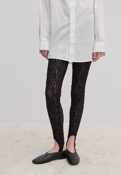 Person wearing a white button-down shirt, slim-fit black stretch-lace Ringo Leggings with stirrup straps, and black flat shoes.
